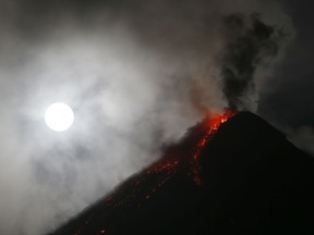 The super blue blood moon sets before dawn as lava cascades down the slopes of Mayon volcano during its sporadic mild eruption as seen from Sto. Domingo township, Albay province around 340 kilometers (200 miles) southeast of Manila, Philippines Thursday, Feb. 1, 2018. It's the first time in 35 years a blue moon has synced up with a supermoon and a total lunar eclipse, or blood moon because of its red hue.