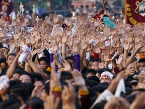 Filipino Roman Catholic devotees raise their hands in prayer during a raucous procession to celebrate the feast day of the Black Nazarene Tuesday, Jan. 9, 2017 in Manila, Philippines. A massive crowd of mostly barefoot Filipino Catholics joined the annual procession of a centuries-old statue of Jesus Christ under tight security.