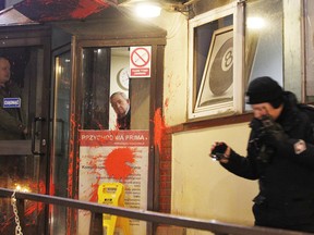 In this photo taken Wednesday, Jan. 17, 2018 a security guard reacts after protesters threw balloons filled with red paint against the headquarters of the conservative ruling Law and Justice party in Warsaw, Poland. The incident occurred late Wednesday after hundreds of people, mostly women, marched through Warsaw calling for a liberalization of the country's abortion laws.