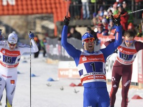 Italy's  Federico Pellegrino celebrates the victory, in front of Sweden's Teodor Peterson. left, and Russia's  Gleb Retivych after the men's 6x1.2km freestyle team sprint final in Dresden, Germany, Sunday, Jan. 14, 2018.