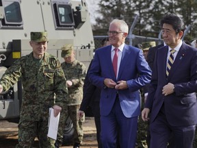 Australian Prime Minister Malcolm Turnbull, center, and Japanese counterpart Shinzo Abe, right, are briefed by a Japan Ground Self-Defense Force officer on a surface-to-air Patriot Advanced Capability-3 (PAC-3) missile interceptor launcher vehicle and a Bushmaster Protected Mobility Vehicle at Narashino Exercise Area in Funabashi, Chiba Prefecture, east of Tokyo Thursday, Jan. 18, 2018.