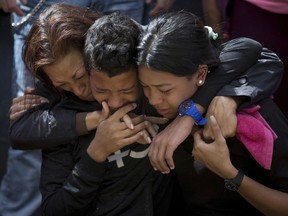 The relatives of Jose Diaz Pimentel, mother Rosa Pimentel, right, and his son Yandribell Diaz and another person, cry during Jose Diaz Pimentel's funeral service at a cemetery in Caracas Venezuela, Saturday, Jan. 20, 2018. Jose Diaz Pimentel and Abraham Agostini, members of the rebel group led by Venezuelan former police Oscar Perez, who died at the beginning of the week in an operation of the security forces, were buried in a controlled manner by the authorities and between protests of their Relatives, who were prevented from accessing the cemetery.