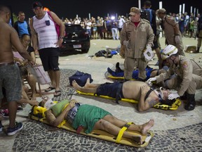 Firefighters give the first aid to people that were hurt after a car drove into the crowded seaside boardwalk along Copacabana beach in Rio de Janeiro.