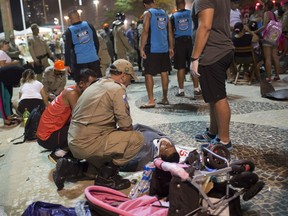 Firefighter gives the first aid to a man that was hurt after a car drove into the crowded seaside boardwalk along Copacabana beach in Rio de Janeiro, Brazil, Thursday, Jan. 18, 2018. Military police said on Twitter that at least 11 people were injured and that the driver has been taken into custody.