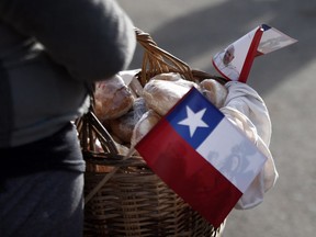 A vendor selling bread has her basket decorated with a Chile and Pope flag, as she stands along the route Pope Francis will use in Temuco, Chile, Wednesday, Jan. 17, 2018.
