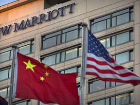 FILE - In this Jan. 11, 2018, file photo, Chinese and American flags fly outside of a JW Marriott hotel in Beijing. Politics weighs more heavily on foreign companies in China than it has in nearly three decades, as companies face pressure on many sides from Chinese President Xi Jinping's more nationalistic stance and twin campaigns to tighten the ruling Communist Party's political control and have it play a more direct role in business.