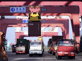 In this Jan. 12, 2018 photo, trucks move shipping containers at a port in Qingdao in eastern China's Shandong province. China's economy expanded at a 6.9 percent pace in 2017, faster than expected and the first annual increase in seven years, the government reported Thursday, Jan. 18, 2017. (Chinatopix via AP)