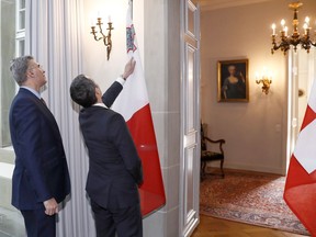 Switzerland's Federal Councillor and Foreign Minister Ignazio Cassis, right, and Carmelo Abela, Malta's Minister of Foreign Affairs, look at the Maltese flag during an official visit in Bern, Switzerland, on Tuesday, Jan. 16, 2018.