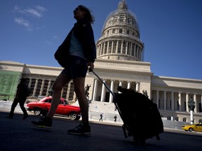 A tourist walks with her suitcase in front of the Capitolio in Havana, Cuba, Thursday, Jan. 18, 2018. President Donald Trump drew cheers from a Cuban-American crowd last summer when he announced that he was rolling back some of Barack Obama's opening to Cuba in order to starve the island's military-run economy of U.S. tourism dollars and ratchet up pressure for regime change.