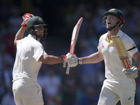 Australia's Shaun Marsh, right, celebrates making 100 runs against England as he runs past his brother Mitchell Marsh during the fourth day of their Ashes cricket test match in Sydney, Sunday, Jan. 7, 2018.