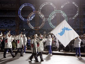 FILE - In this Feb. 10, 2006, file photo, Korea's flag-bearers Bora Lee and Jong-In Lee, carrying a unification flag lead their teams into the stadium during the 2006 Winter Olympics opening ceremony in Turin, Italy. When athletes of the rival Koreas walked together behind a single flag for the first time since their 1945 division at the start of the 2000 Sydney Olympics, it was a highly emotional event that came on the wave of reconciliation mood following their leaders' first-ever summit talks. Eighteen years later, now, the Koreas are pushing to produce a similar drama during the upcoming Pyeongchang Olympics. But they haven't generated as much enthusiastic supports as they had both at home and abroad.