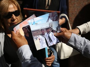 Family members of the crew of the missing ARA San Juan submarine show photos of their loved ones as they gather outside Russia's embassy in Buenos Aires, Argentina, Monday, Jan. 15, 2018. Monday marks two months since the disappearance of the Argentine naval submarine, and families see the continuing participation of specialized Russian vessels in the search operation as the last hope in locating the missing submarine and determining what happened to its 44 crew members.