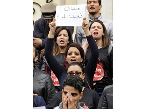 A woman holds a poster reading "What are we waiting for", during a protest against the 2018 budget in Tunis, Tuesday, Jan.9, 2018. Tunisia's prime minister is promising to crack down on rioters after violent protests over price hikes that left one person dead.