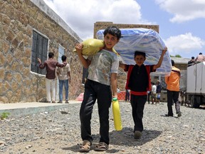 FILE - In this May 9, 2015 file photo, boys carry relief supplies to their families who fled fighting in the southern city of Aden, in Taiz, Yemen. Saudi Arabia said Sunday, Jan. 21, 2018, that  the coalition it is leading in Yemen will provide $1.5 billion in new humanitarian aid for international relief organizations working in the impoverished country. It comes as aid groups say coalition airstrikes are destroying critical infrastructure and that the coalition needs to do more to facilitate the delivery of fuel, food and medicine at Yemeni ports.