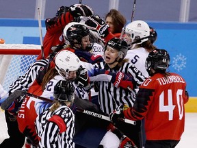 Officials attempt to separate players from Canada and the United States late in the game on Feb. 15, 2018.