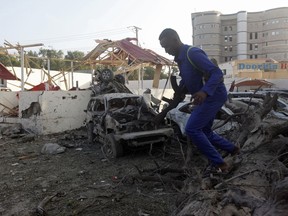 A soldier climbs over destroyed vehicles near following a twin bomb attack in the capital Mogadishu, Somalia Saturday, Feb. 24, 2018. Two car bomb blasts rocked Somalia's capital Friday evening, followed by gunfire, police said, and an ambulance service said more than a dozen had been killed.