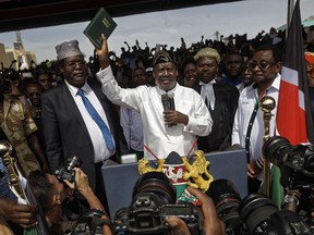 FILE - In this Tuesday, Jan. 30, 2018 file photo, opposition politician Miguna Miguna, left, stands next to opposition leader Raila Odinga, center, lawyer Tom "T.J." Kajwang, center-right, and politician James Orengo, right, as Odinga holds a bible aloft after swearing an oath during a mock "swearing-in" ceremony at Uhuru Park in downtown Nairobi, Kenya. Lawyers are demanding that Kenyan police release Miguna who has been charged with witnessing last week's mock inauguration of opposition leader Raila Odinga and remains detained despite a court order on Friday for his release.