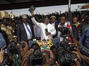 Opposition leader Raila Odinga holds a bible aloft after swearing an oath during a mock "swearing-in" ceremony at Uhuru Park in downtown Nairobi, Kenya Tuesday, Jan. 30, 2018. Odinga was sworn-in as "the people's president" during a mock "inauguration", in protest of President Uhuru Kenyatta's new term following the divisive 2017 election, and despite the government's warning that the event would be considered treason.
