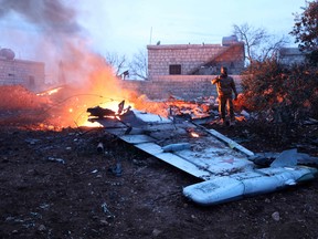 A picture taken on February 3, 2018, shows a Rebel fighter taking a picture of a downed Sukhoi-25 fighter jet in the the Syrian city of Saraqib, southwest of Aleppo. Rebel fighters shot down a Russian plane over Syria's northwest Idlib province and captured its pilot, the Syrian Observatory for Human Rights said.