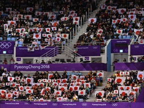 Supporters hold up Japanese flags in the stands during the men's figure skating short program.