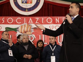 Vincenzo Accardo, head of Torre Del Greco seamen's group, left, stands next to founder of 5-Star Movement Beppe Grillo as they listen to the movement's premier canditate Luigi Di Maio during an electoral rally in view of the March 4 general elections, in Torre Del Greco, near Naples, southern Italy, Monday, Feb. 12, 2018. Accardo angrily told a rally last week that he had asked all the main parties to come to this town and learn about its problems, but only 5-Star leader Luigi Di Maio replied.