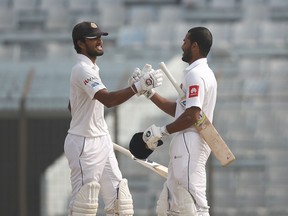 Sri Lanka's captain Dinesh Chandimal, left, congratulates teammate Roshen Silva after scoring hundred runs during the fourth day of their first test cricket match against Bangladesh in Chittagong, Bangladesh, Saturday, Feb. 3, 2018.