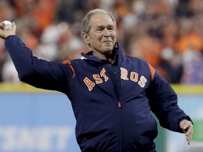 FILE- In this Sunday, Oct. 29, 2017 file photo, former President George W. Bush throws the ceremonial first pitch before Game 5 of baseball's World Series between the Houston Astros and the Los Angeles Dodgers, in Houston. Bush spoke Thursday at a summit in Abu Dhabi put on by the Milken Institute, an economic think tank based in Santa Monica, California.