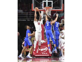 Arkansas' Daniel Gafford comes down with a rebound between Kentucky's P.J. Washington, left, Kevin Knox (5) and Jarred Vanderbilt (2) during the first half of an NCAA college basketball game Tuesday, Feb. 20, 2018, in Fayetteville, Ark.