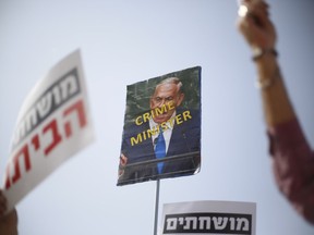 Protesters hold sings and flags during a protest against corruption and Israel's Prime Minister Benjamin Netanyahu in Tel Aviv, Israel, Friday, Feb. 16, 2018.