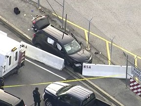 In this image made from video and provided by WUSA TV-9, authorities investigate the scene of a shooting at Fort Meade, Md. on Wednesday, Feb. 14, 2018. A suspect has been held, taken from the black SUV that stopped at barrier after a shooting outside National Security Agency. (WUSA TV-9 via AP)