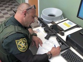 In this Feb. 16, 2018, photo provided by Ben Dickmann, a deputy at the Broward County sheriff's office in Ft. Lauderdale, Fla., processes paperwork to take possession of and destroy Dickmann's AR-style firearm. Dickmann decided to turn in his weapon after the shooting at Marjory Stoneman Douglas High School in nearby Parkland, Fla.