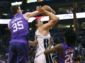 Denver Nuggets' Nikola Jokic, center, is fouled as he shoots between Phoenix Suns' Dragan Bender (35) and Josh Jackson during the first half of an NBA basketball game Saturday, Feb. 10, 2018, in Phoenix.