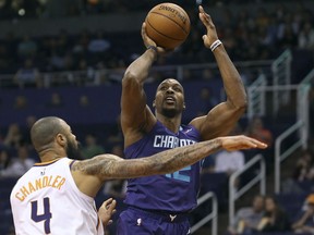 CORRECTS TO SUNDAY NOT SATURDAY - Charlotte Hornets center Dwight Howard, right, shoots over the defense of Phoenix Suns' Tyson Chandler during the first half of an NBA basketball game Sunday, Feb. 4, 2018, in Phoenix.