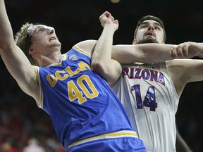 UCLA center Thomas Welsh (40) and Arizona's Dusan Ristic (14) wait for a rebound during the second half of an NCAA college basketball game Thursday, Feb. 8, 2018, in Tucson, Ariz. UCLA defeated Arizona 82-74.