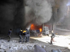 In this photo released on Tuesday Feb. 20, 2018 provided by the Syrian Civil Defense group known as the White Helmets, shows members of the Syrian Civil Defense extinguishing a store during airstrikes and shelling by Syrian government forces, in Ghouta, a suburb of Damascus, Syria. Intense Syrian government shelling and airstrikes of rebel-held Damascus suburbs killed at least 100 people since Monday in what was the deadliest day in the area in three years, a monitoring group and paramedics said Tuesday. (Syrian Civil Defense White Helmets via AP)