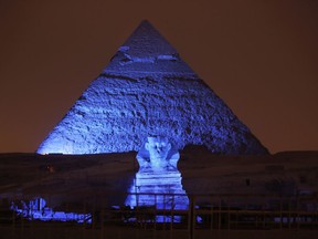 FILE - In this Saturday, Oct. 24, 2015, file photo, the Sphinx and the historical site of the Giza Pyramids are illuminated with blue light, as part of the celebration of the 70th anniversary of the United Nations in Giza, just outside Cairo, Egypt. Archaeologists in Egypt say they have discovered a 4,400-year-old tomb near the pyramids outside Cairo. Egypt's Antiquities Ministry announced the discovery Saturday and said the tomb likely belonged to a high-ranking official known as Hetpet during the 5th Dynasty of ancient Egypt.
