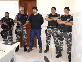 Military police standing with who they identify as Jose Irandir Cardoso at a police station in Breves, Para state, Brazil.