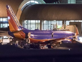 In this Monday, Feb. 12, 2018 photo, a Southwest Airlines plane sits it a gate after passengers had to evacuate before takeoff because of a fire at John Wayne Airport in Santa Ana, Calif. Federal Aviation Administration spokesman Allen Kenitzer says the blaze was in the airliner's auxiliary power unit and was extinguished with the plane's fire suppression system