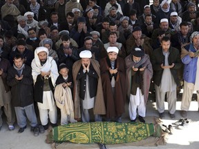 FILE - In this Dec. 29, 2017 file photo, Afghan people offer funeral prayers behind the body of a civilian killed in a suicide attack on a Shiite cultural center in Kabul, Afghanistan. The U.N. mission in Afghanistan says the number of civilian casualties in the country's conflict decreased by 9 percent in 2017. The U.N. 2017 Annual Report on the Protection of Civilians in Armed Conflict in Afghanistan was released Thursday, Feb. 15, 2018.