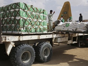In this Saturday, Feb. 3, 2018 photograph, a relief worker signals a forklift driver unloading aid carried into Yemen by the Saudi military in Marib, Yemen. Saudi Arabia, which is at war with the Shiite rebels who hold Yemen's capital, is also delivering aid to the Arab world's poorest country.