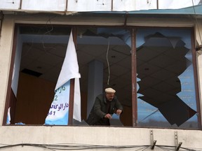 An Afghan shopkeeper removes the shuttered glasses of his shop in the aftermath of Saturday's suicide attack in Kabul, Afghanistan, Sunday, Jan. 28, 2018. U.S. President Donald Trump is condemning "the despicable car bombing attack" in the Afghan capital of Kabul.