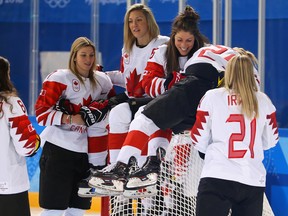 Rebeca Johnston of the Canadian women's hockey team has a laugh as she helps her captain Marie-Philip Poulin get up on top of the net for some team pictures.