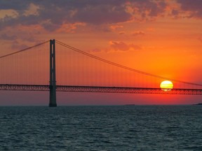 FILE - In this May 31, 2002 file photo, the sun sets over the Mackinac Bridge and the Mackinac Straits as seen from Lake Huron. The bridge is the dividing line between Lake Michigan to the west and Lake Huron to the east. President Donald Trump again is trying to drastically reduce or eliminate federal support for cleanups of some iconic U.S. waterways. His proposed budget would slash Environmental Protection Agency funding for Great Lakes and Chesapeake Bay restoration programs by 90 percent. It would kills all EPA spending on programs supporting other waters including San Francisco Bay, the Gulf of Mexico and Puget Sound. The administration made a similar attempt last year but Congress refused to go along.