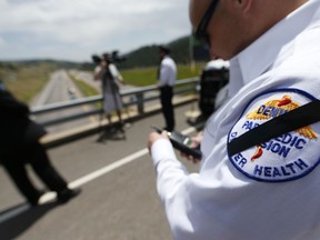 FILE - In this July 9, 2015 file photo, a piece of black tape runs through the shoulder patch of Eric Gilles, a paramedic with Denver Health, as he waits for a procession to pass along Interstate 70 in Golden, Colo. with the body of Flight for Life helicopter pilot Patrick Mahany. He was killed in a July 3, 2015 helicopter crash in Frisco, Colo. which also critically injured flight nurse David Repsher. Repsher's lawyers said Thursday, Feb. 1, 2018 the helicopter's manufacturer and operator have agreed to pay Repsher a $100 million settlement.