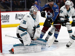 San Jose Sharks goaltender Martin Jones, left, makes a save of a shot as Colorado Avalanche center Colin Wilson, center, and Sharks right wing Joonas Donskoi, of Finland, jostle for position in the first period of an NHL hockey game Tuesday, Feb. 6, 2018, in Denver.