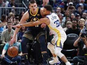 Denver Nuggets center Nikola Jokic, left, tries to move the ball as Golden State Warriors guard Stephen Curry defends in the first half of an NBA basketball game Saturday, Feb. 3, 2018, in Denver.