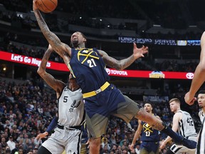 Denver Nuggets forward Wilson Chandler, front, reaches over San Antonio Spurs guard Dejounte Murray for the ball during the first half of an NBA basketball game Tuesday, Feb. 13, 2018, in Denver.