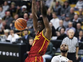 Southern California forward Chimezie Metu hangs from the rim after dunking next to Colorado forward Dallas Walton during the first half of an NCAA college basketball game Wednesday, Feb. 21, 2018, in Boulder, Colo.