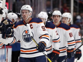 Edmonton Oilers center Connor McDavid, front, is congratulated as he passes the team box after scoring his first of two goals in the third period of an NHL hockey game against the Colorado Avalanche, Sunday, Feb. 18, 2018, in Denver.