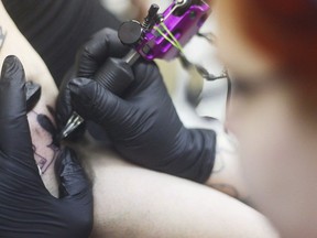 A tattoo artist works on a client in in Kenai, Alaska in a March 14, 2105 file photo. Setting up tattoo parlours and needle exchange programs in federal prisons would help reduce hepatitis C rates, the Correctional Service tells Public Safety Minister Ralph Goodale.